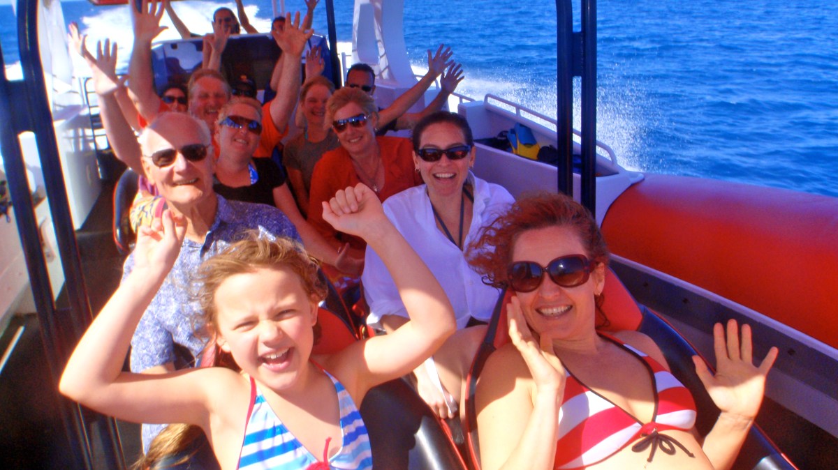 a group of people sitting in a boat on a body of water