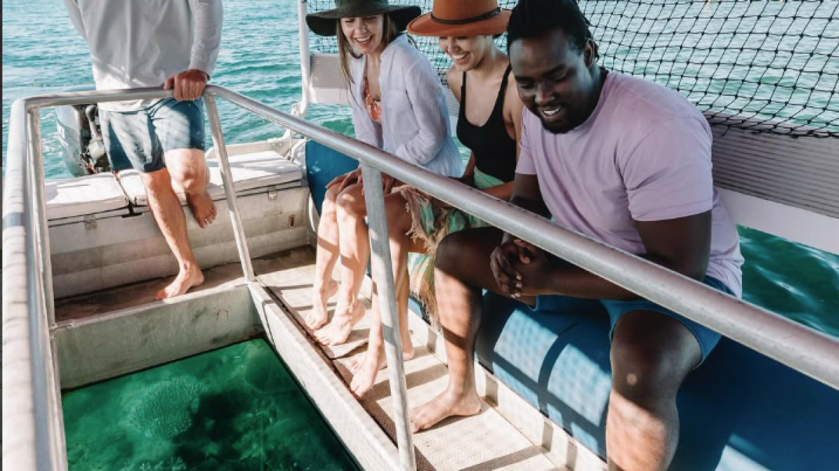 People on a boat looking through a glass-bottom section at water below.
