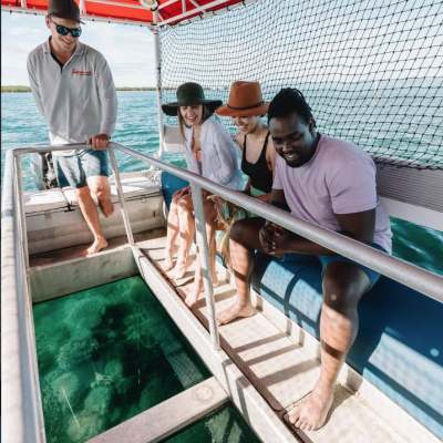 People on a boat looking through a glass-bottom section at water below.