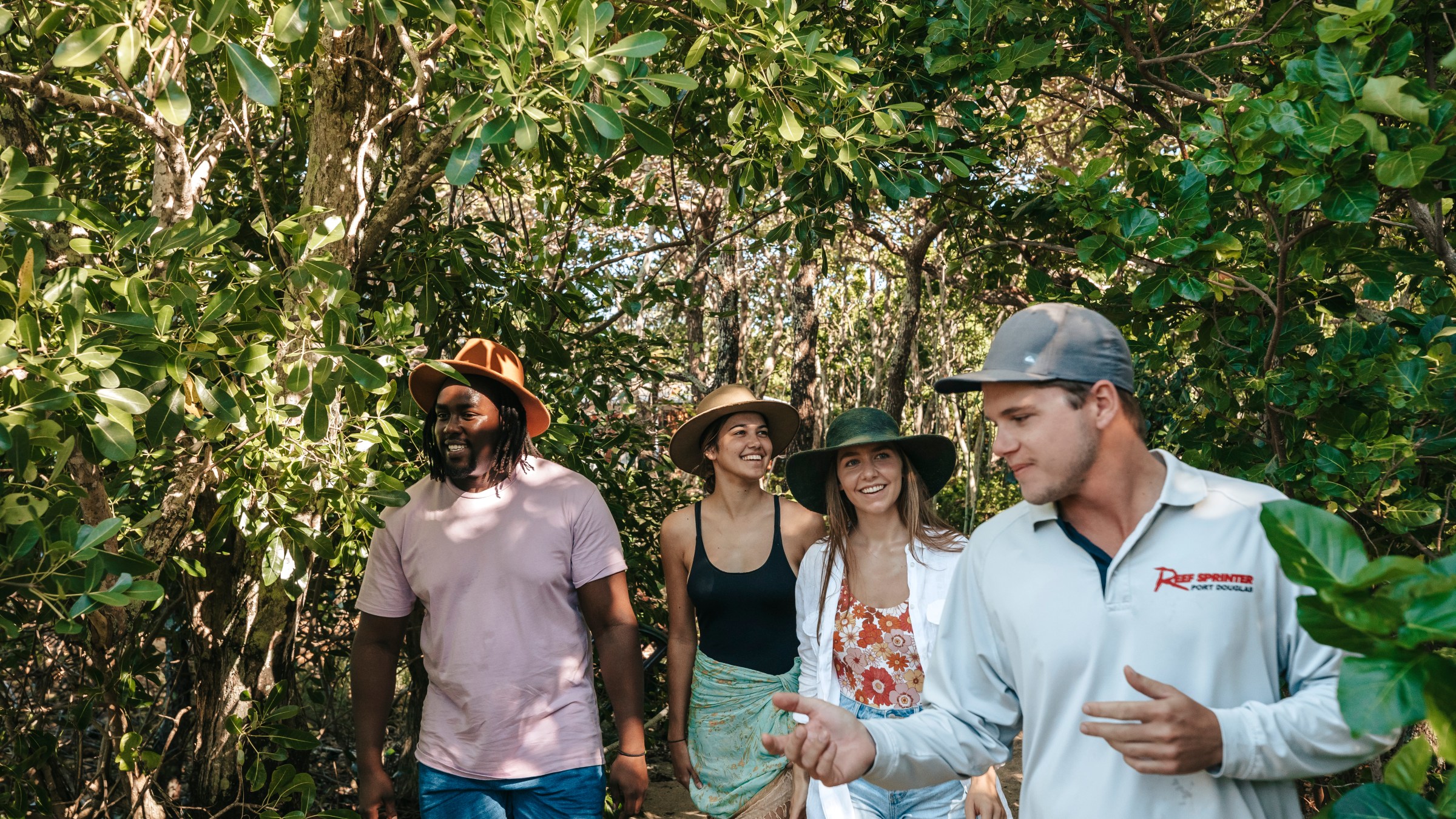 Group walking through a forest path, led by a guide, surrounded by lush greenery.